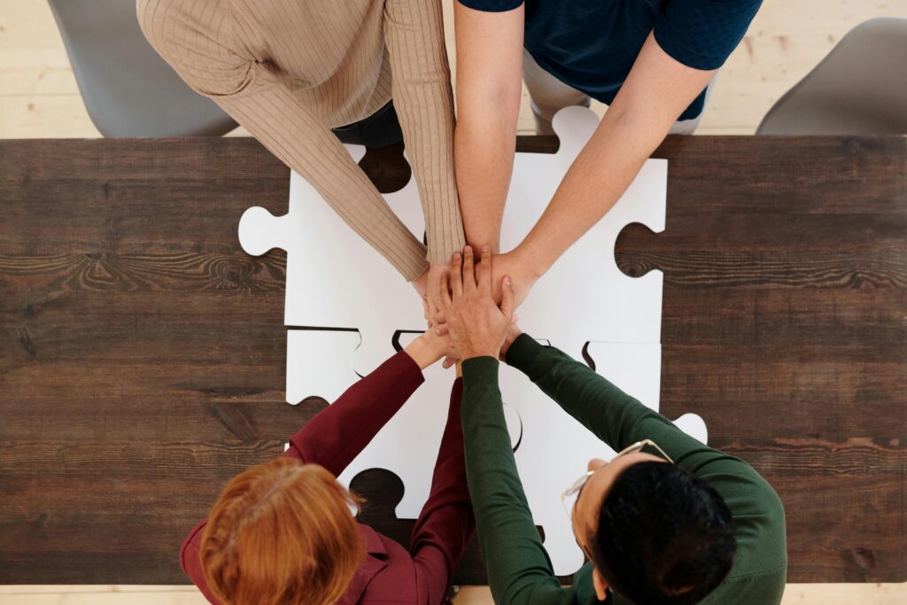 pexels-photo-6147373-6147373 Engaging image of diverse people's hands coming together on puzzle pieces, symbolizing unity.